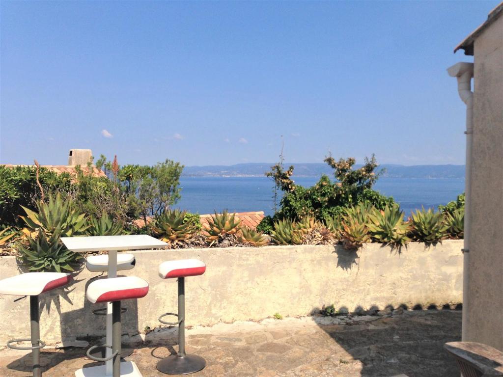 un patio con 2 taburetes y vistas al océano en Studio climatisé île naturiste du Levant en Hyères