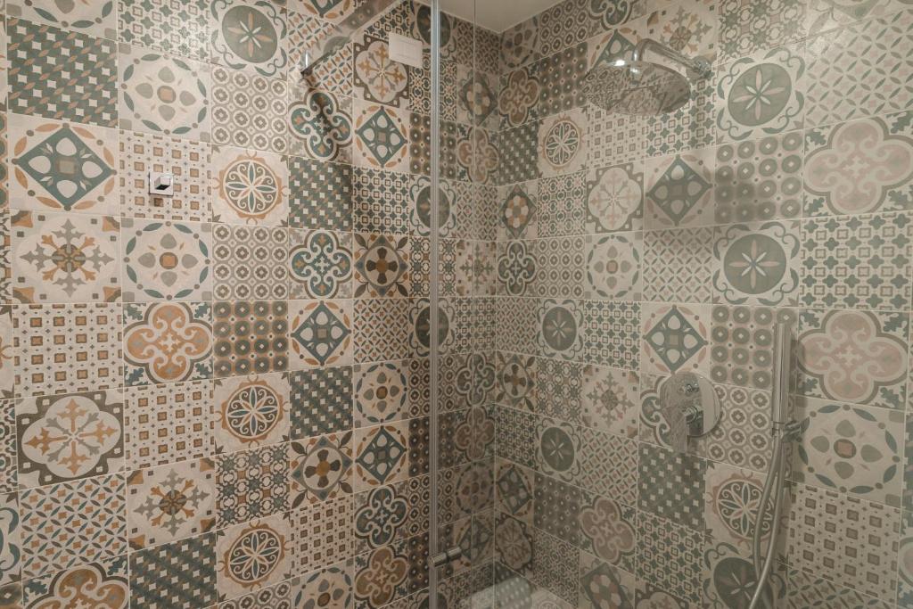 a bathroom with a shower with a tiled wall at Sicilia's Art Hotel & Spa in Acitrezza