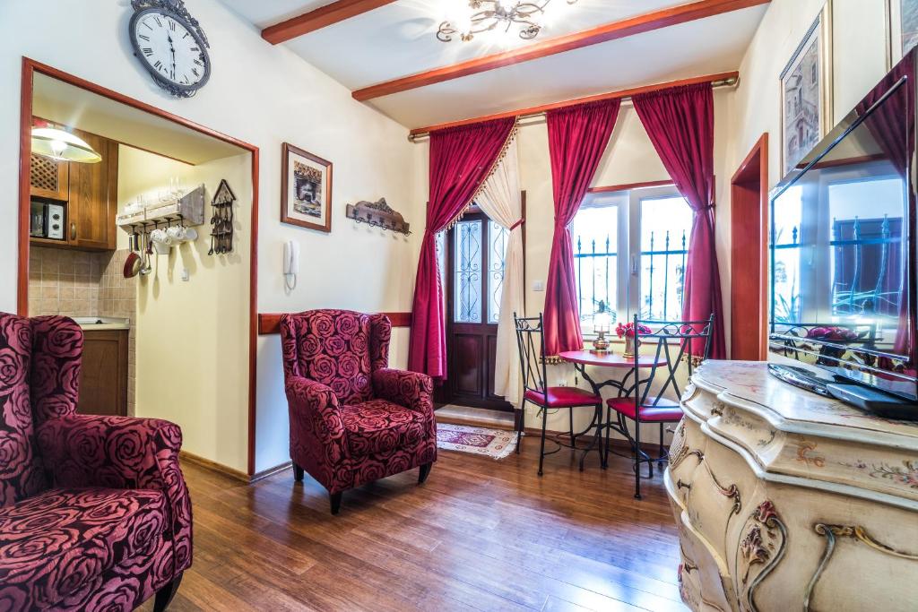 uma sala de estar com mesa e cadeiras e um relógio em Emperor's Suites em Split