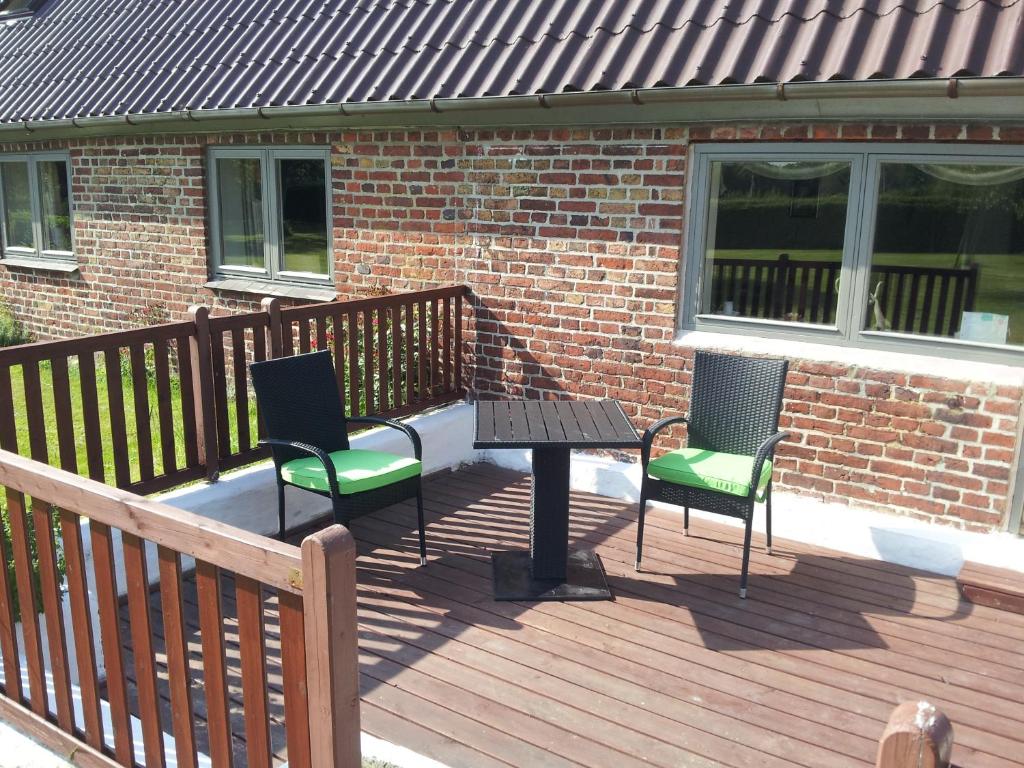 a wooden deck with two chairs and a table at Lilleledgaard Apartment in Ringkøbing
