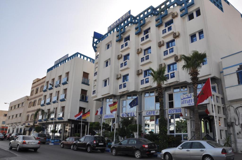 un gran edificio blanco con coches estacionados frente a él en Hotel Annakhil en Nador