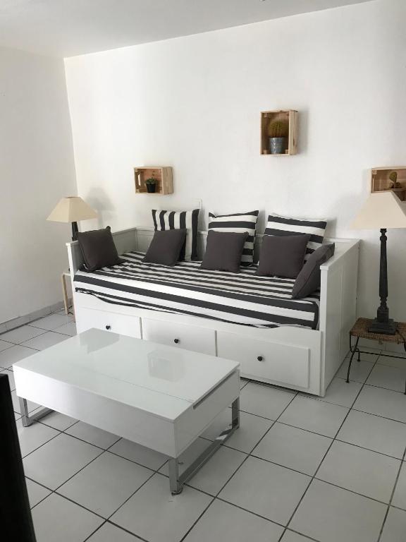 - un canapé blanc avec des oreillers noirs et blancs dans le salon dans l'établissement STUDIO TOUT A PIEDS, à Sanary-sur-Mer