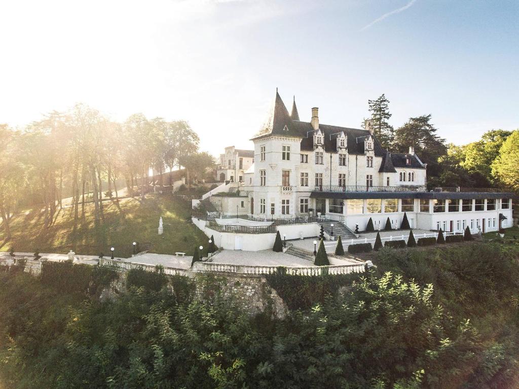 ein großes weißes Haus auf einem Hügel in der Unterkunft Chateau Le Prieuré Saumur - La Maison Younan in Chènehutte-les-Tuffeaux