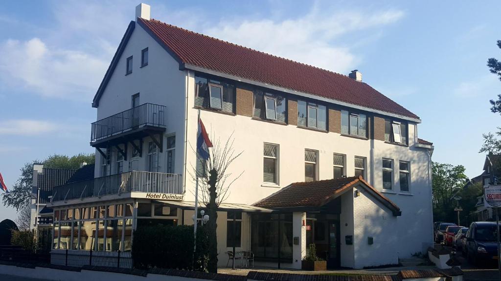 un grand bâtiment blanc avec un toit rouge dans l'établissement Zorn Hotel Duinlust, à Noordwijk aan Zee