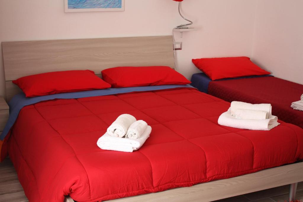 2 Betten mit roter Bettwäsche und weißen Handtüchern darauf in der Unterkunft House of colours in Alghero