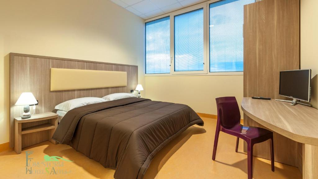 a bedroom with a bed and a desk with a computer at Foresteria Sant'Anna in Ferrara