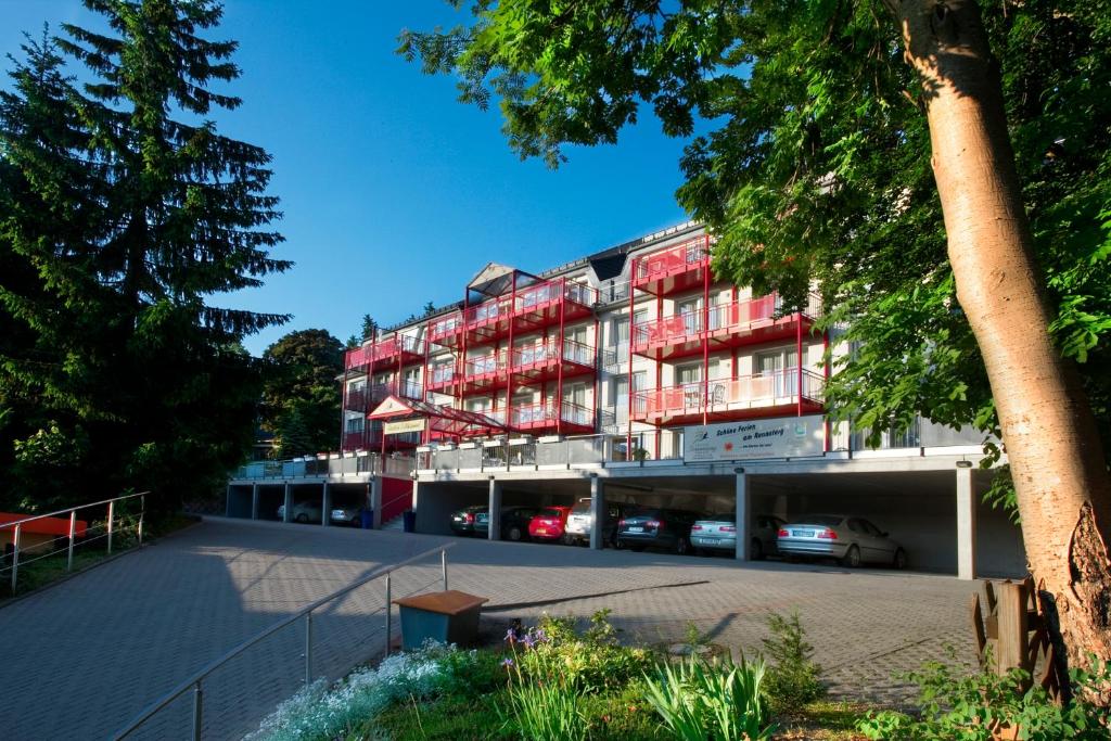 ein Apartmenthaus mit roten Balkonen und einem Parkplatz in der Unterkunft Chalet Sonnenhang Oberhof in Oberhof