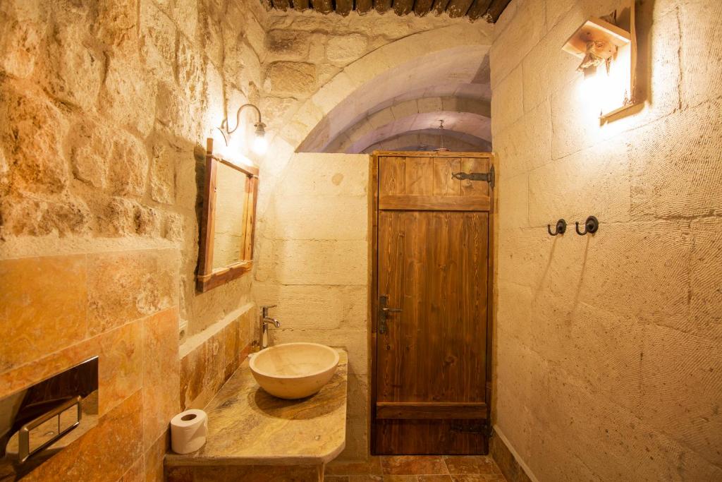 a bathroom with a sink and a wooden door at kayadibi cave hotel in Ürgüp