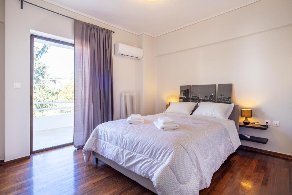 sypialnia z dużym łóżkiem i dużym oknem w obiekcie Kleio - Spacious apartment in Glyfada w Atenach
