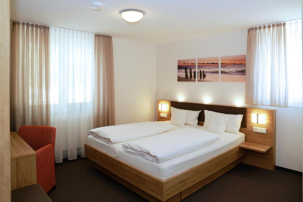 a bedroom with a large bed and a red chair at Hotel Gasthof Schützen in Laupheim