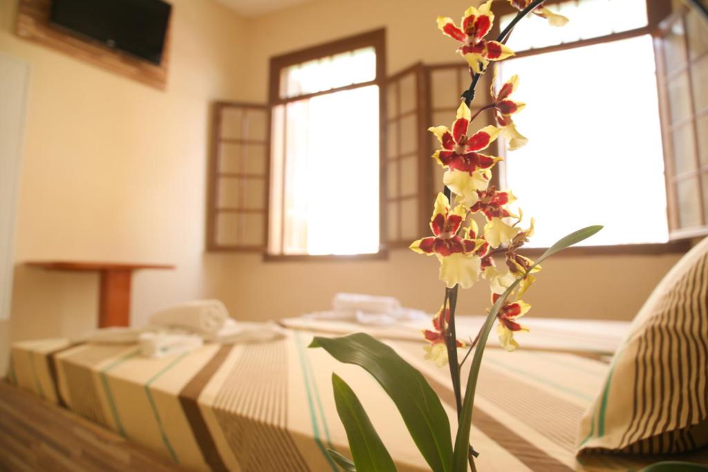 Hotel Hot Brás في ساو باولو: غرفة مع سرير مع مزهرية مع الزهور