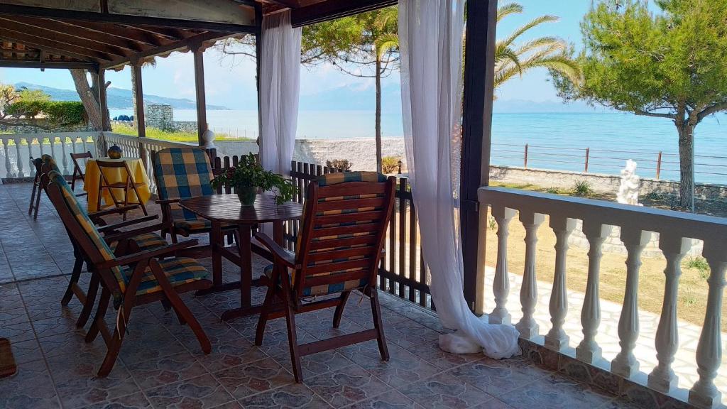 un porche con mesa, sillas y el océano en Sea Whispers Beach House, en Alykes