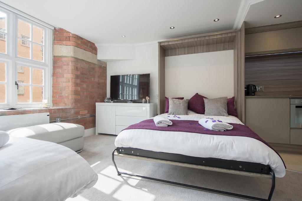 ein Schlafzimmer mit einem großen Bett und einer Ziegelwand in der Unterkunft ChocoLets - The Quality Suite in York