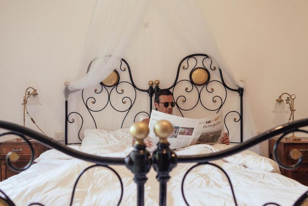 a man sitting in bed reading a newspaper at Antico Borgo Sanda Lago Maggiore in Casalzuigno