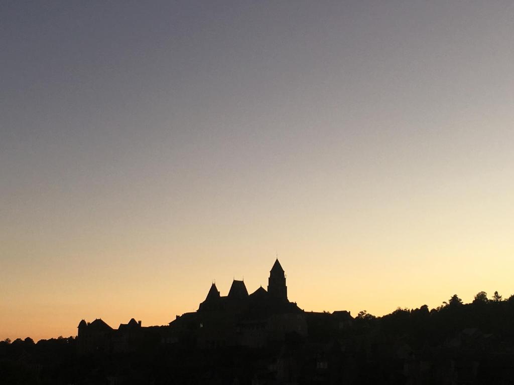une silhouette d'un bâtiment sur une colline au coucher du soleil dans l'établissement Les Roches Bleues, à Uzerche