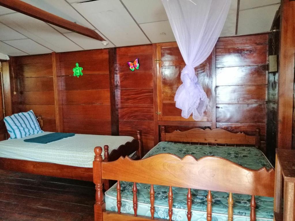 two beds in a room with wooden walls at Finca Magdalena Eco Lodge in Balgue
