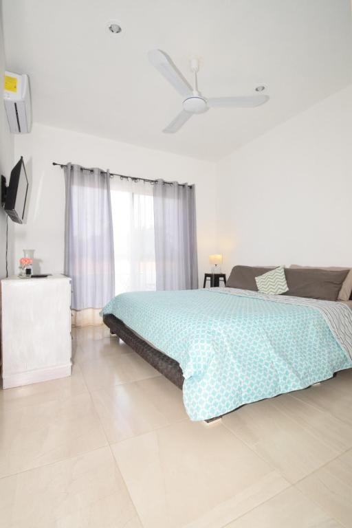 a white bedroom with a bed and a window at Carlota Guest House in Cozumel