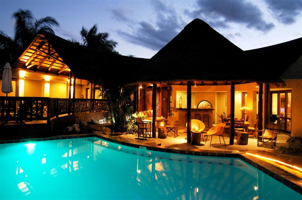 a swimming pool in front of a house at night at La Lechere Guest House in Phalaborwa