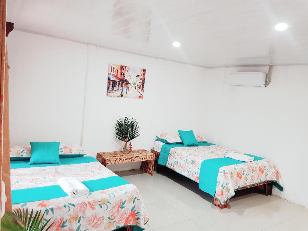 a white room with two beds and a table at Hotel Maguey in Chilamate
