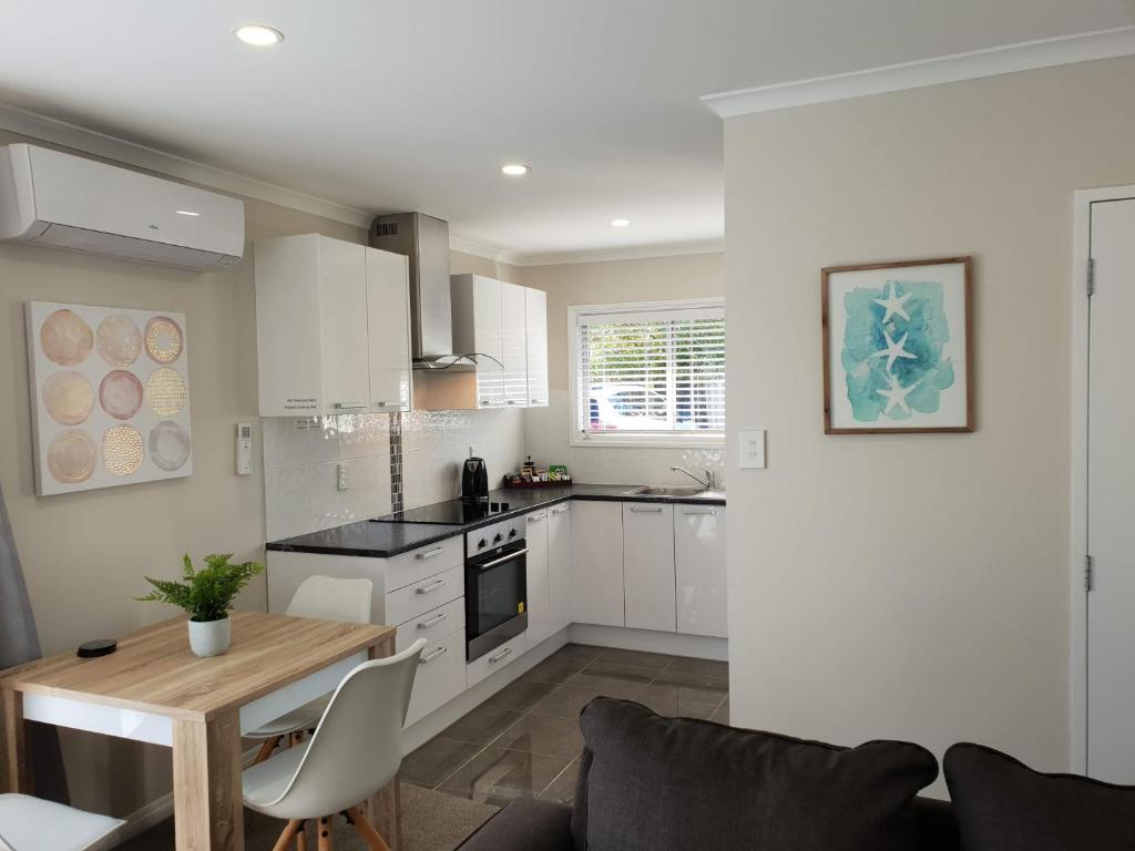 a kitchen with white cabinets and a wooden table at Rose Apartments Unit 5 Central Rotorua- Accommodation & Spa in Rotorua