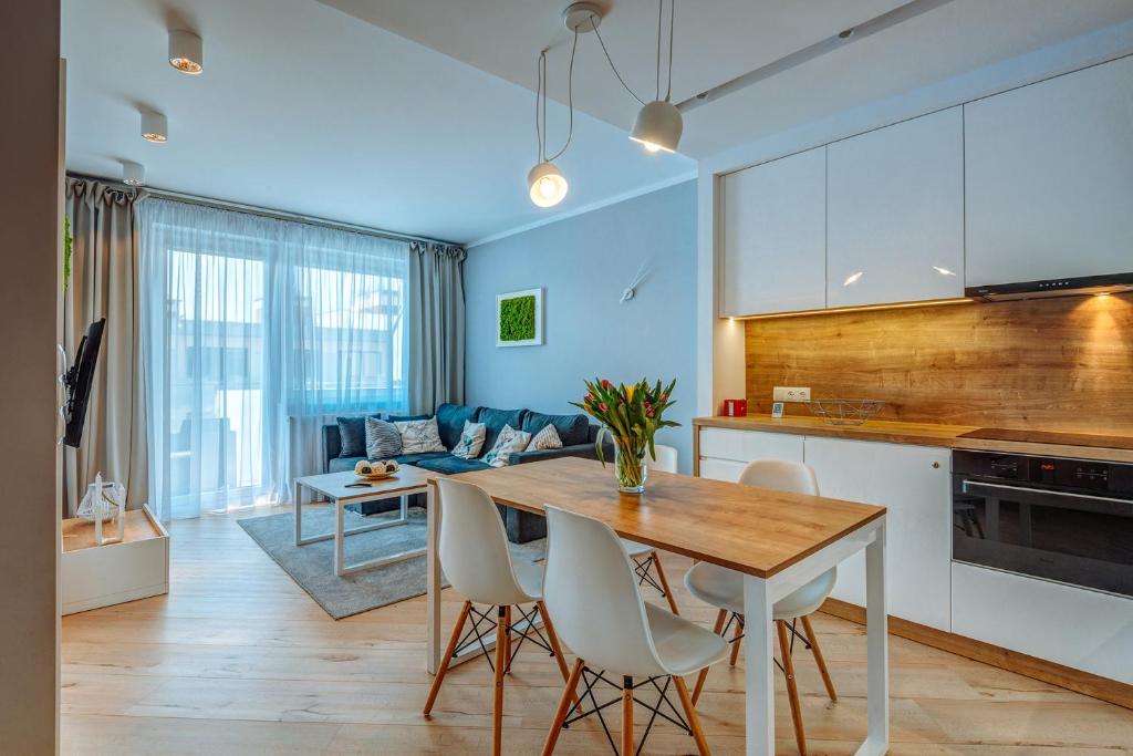 een keuken en een woonkamer met een tafel en stoelen bij Apartament Scandi - Bliżej Morza in Kołobrzeg