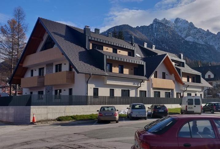 ein großes Gebäude mit Autos auf einem Parkplatz in der Unterkunft Vila Mojca - Studio 13 in Kranjska Gora