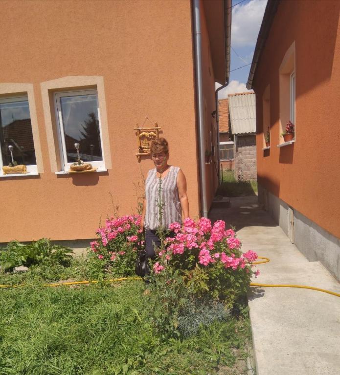 a woman standing next to a bunch of pink flowers at Apartmani ,,Bato,, in Sjenica