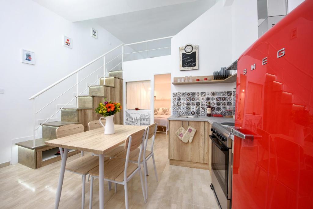 une cuisine avec une table en bois et des placards rouges dans l'établissement La vecchia bottega del Nonno - Corfu, à Corfou