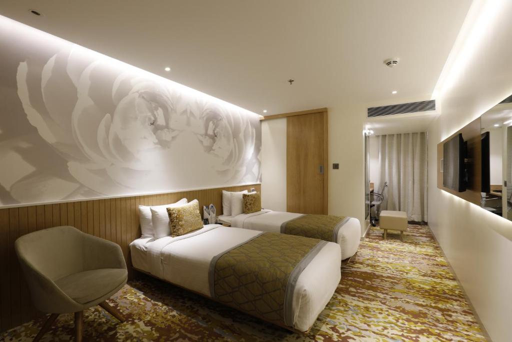 a hotel room with two beds and a chair at Effotel by Sayaji Vadodara in Vadodara
