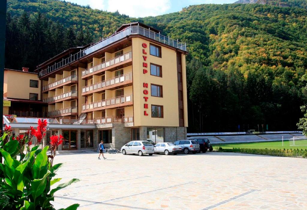 un grande edificio con auto parcheggiate in un parcheggio di Olymp Hotel a Teteven