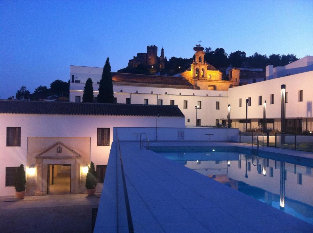 
a hotel room with a pool and a large building at Hotel Convento Aracena & SPA in Aracena
