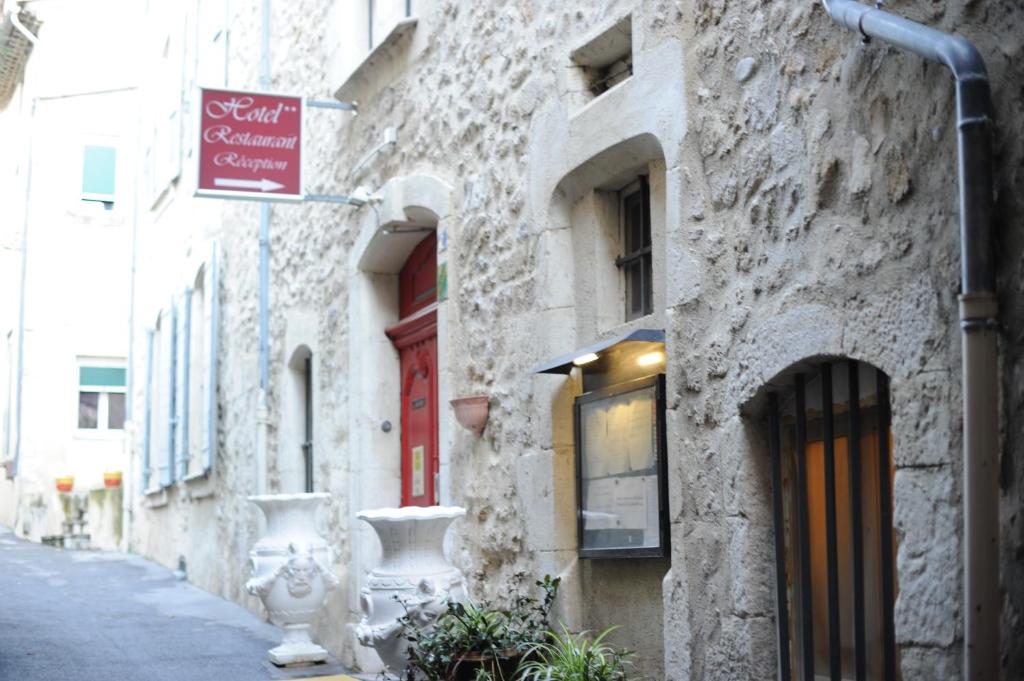 a stone building with a sign on the side of a street at Logis Hotel le Prieuré in Bourg-Saint-Andéol