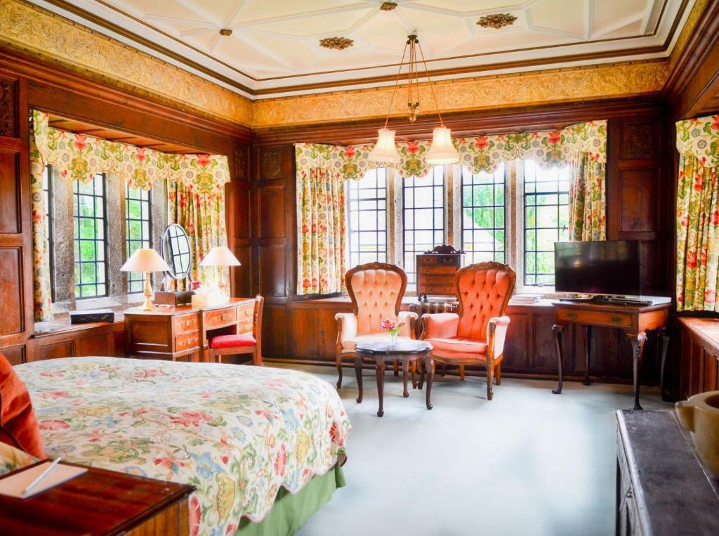 a bedroom with a bed and a desk and chairs at Lewtrenchard Manor in Lewdown