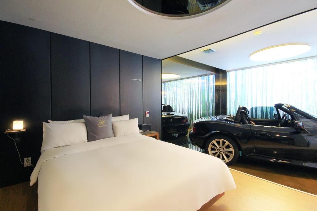 una camera con un letto bianco e una macchina nera di H Drive Hotel a Iksan