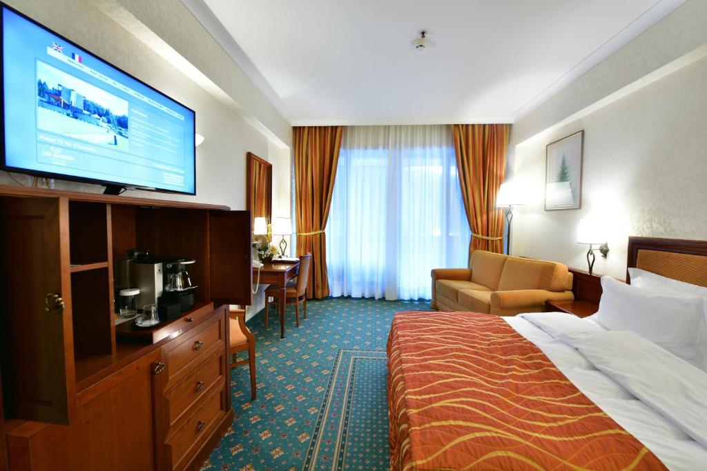 um quarto de hotel com uma cama e uma televisão de ecrã plano em Lux Garden Hotel em Azuga