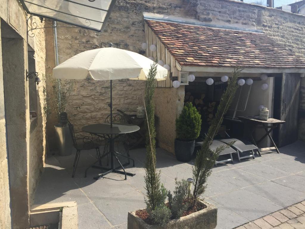 eine Terrasse mit einem Tisch und einem Sonnenschirm in der Unterkunft Le Gite du Petit Lavoir in Bèze