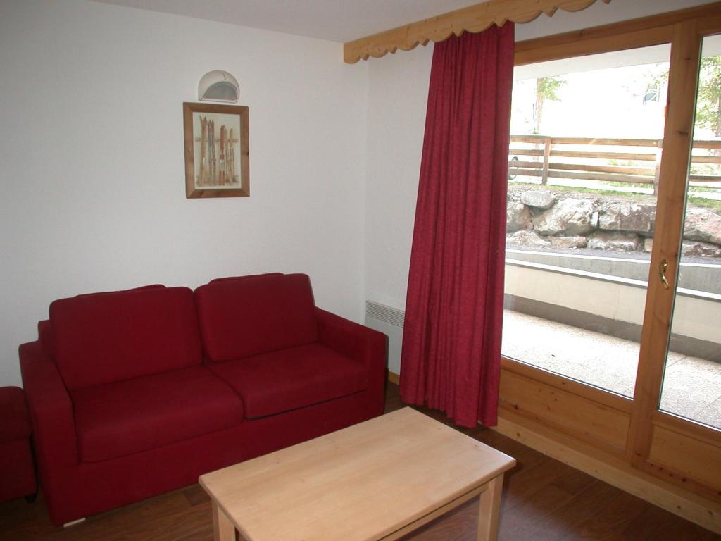 a living room with a red couch and a window at L&#39;Ecrin des Neiges in Vars