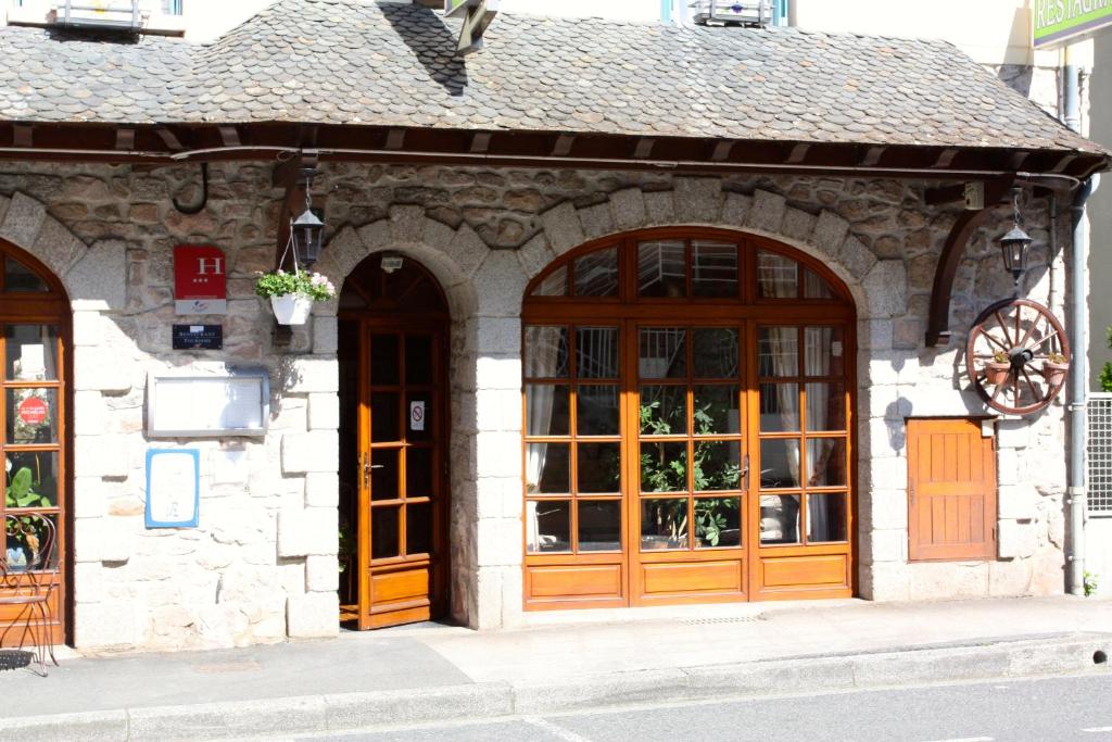- un bâtiment en pierre avec des portes et des fenêtres en bois dans l'établissement Hotel Restaurant des Deux Vallées, à Entraygues-sur-Truyère