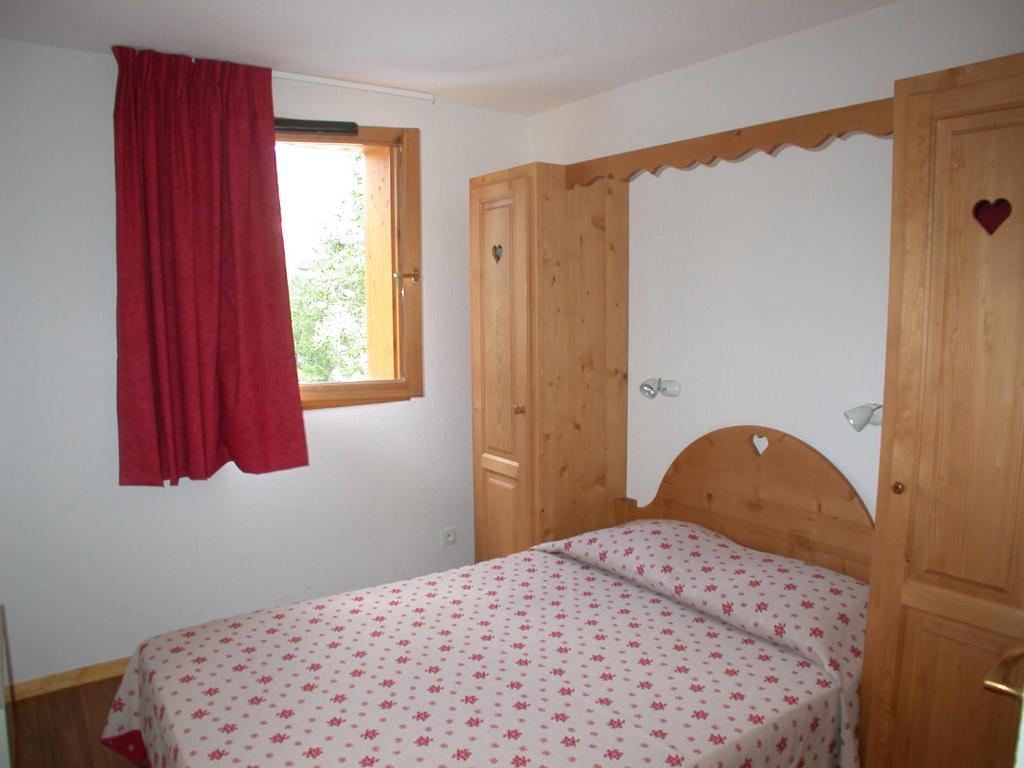 a bedroom with a bed with a red curtain and a window at L&#39;Ecrin des Neiges in Vars