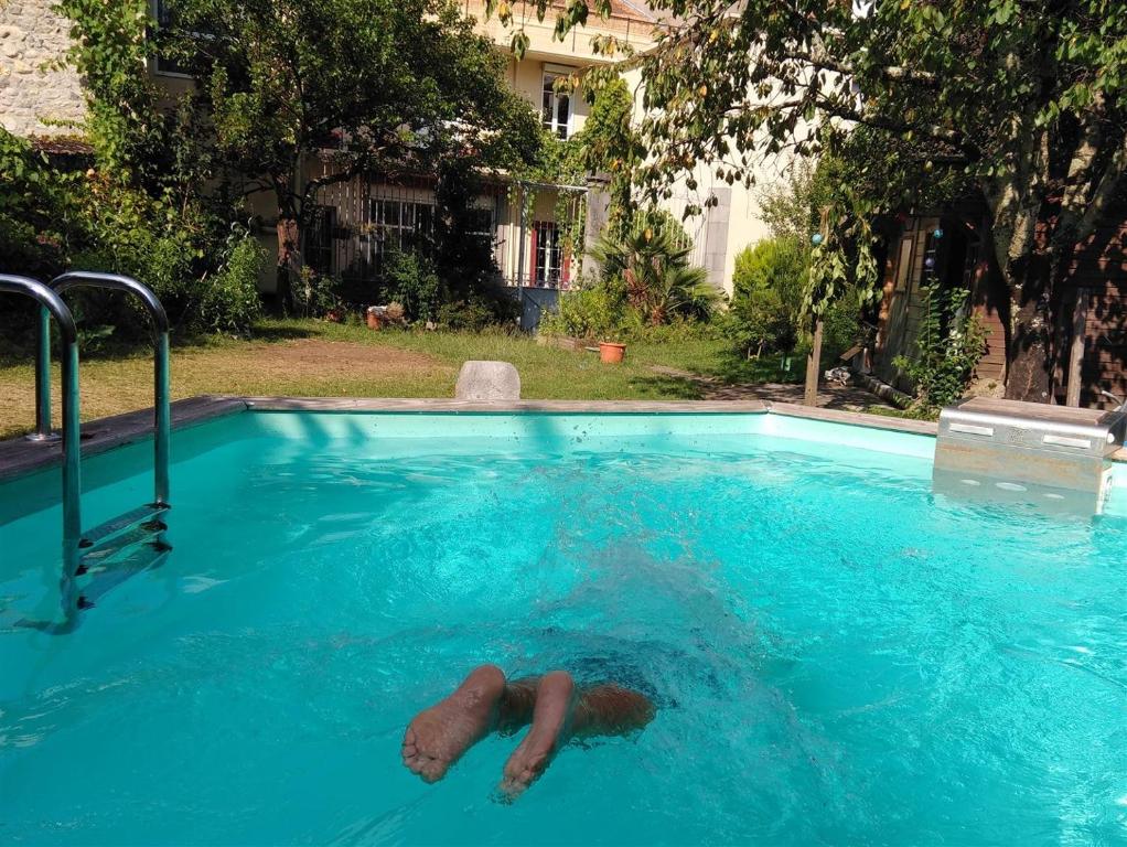 eine Person, die in einem Schwimmbad liegt in der Unterkunft Le Patio Gironnais in Saint-Girons