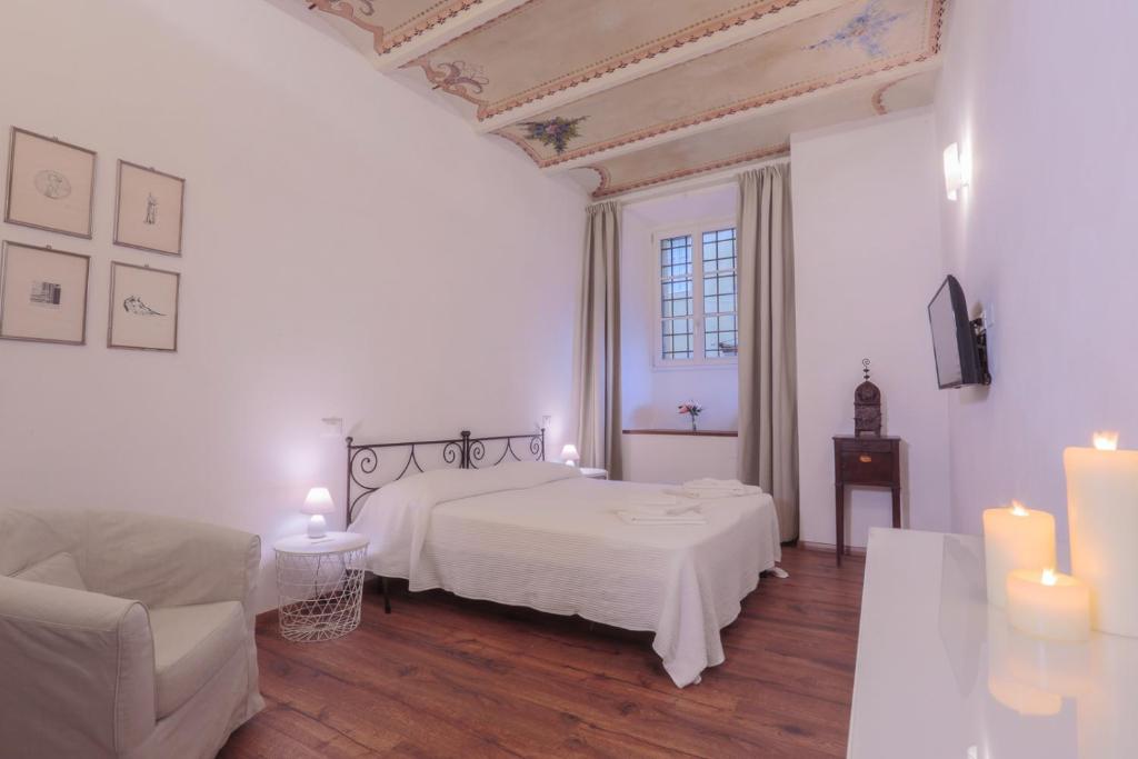 a white bedroom with a bed and a couch and candles at San Pierino Charming Rooms in Lucca