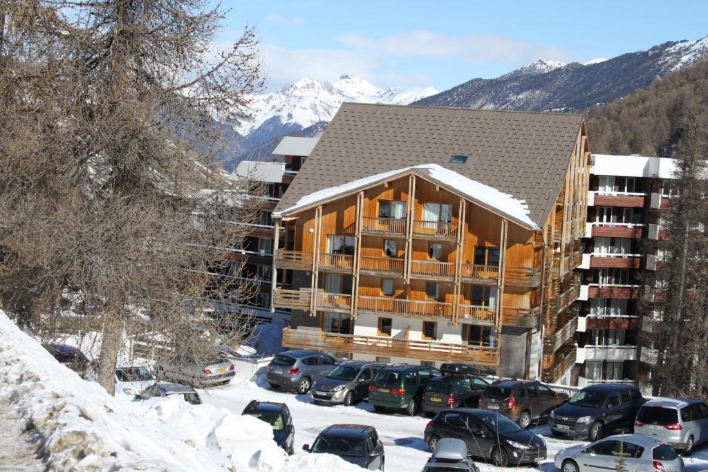a large building with cars parked in a parking lot at L&#39;Ecrin des Neiges in Vars