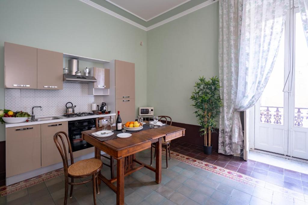 uma cozinha com uma mesa de madeira e cadeiras numa cozinha em Lettera Living em Catânia
