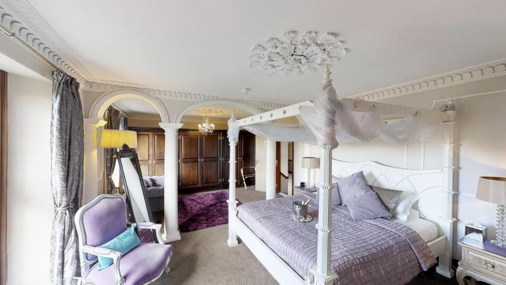 een slaapkamer met een hemelbed en een paarse stoel bij Redhill House BRS Airport in Redhill