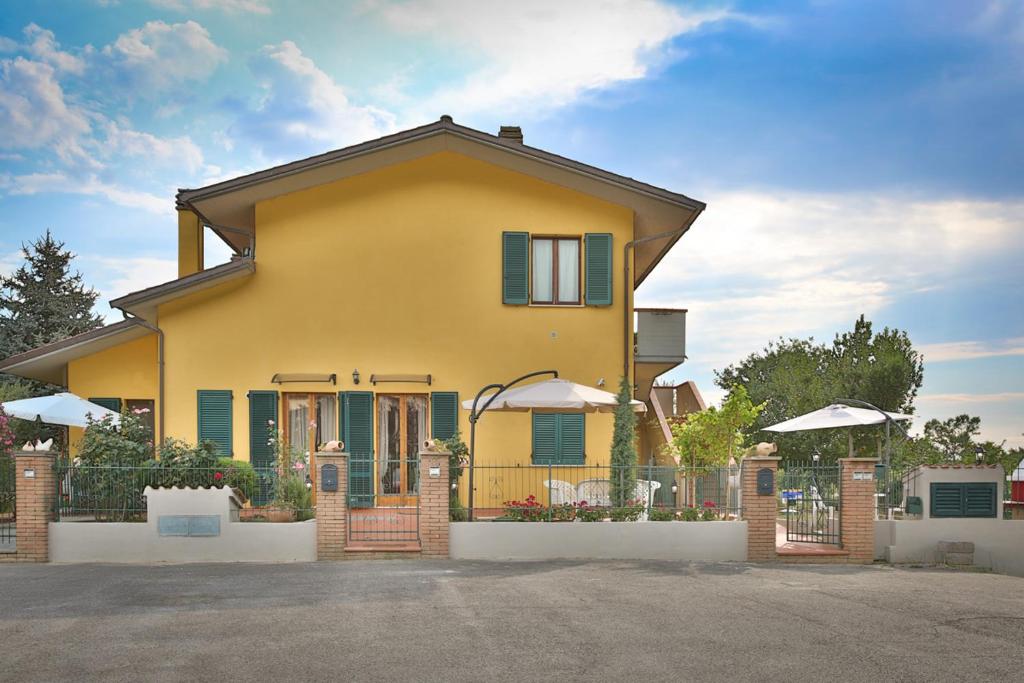 a yellow house with green shutters and a fence at Venere in Borghetto