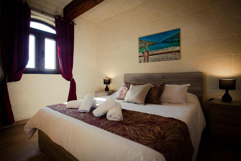 a bedroom with a large bed with white pillows at Soleil B&B Gozo in Għarb