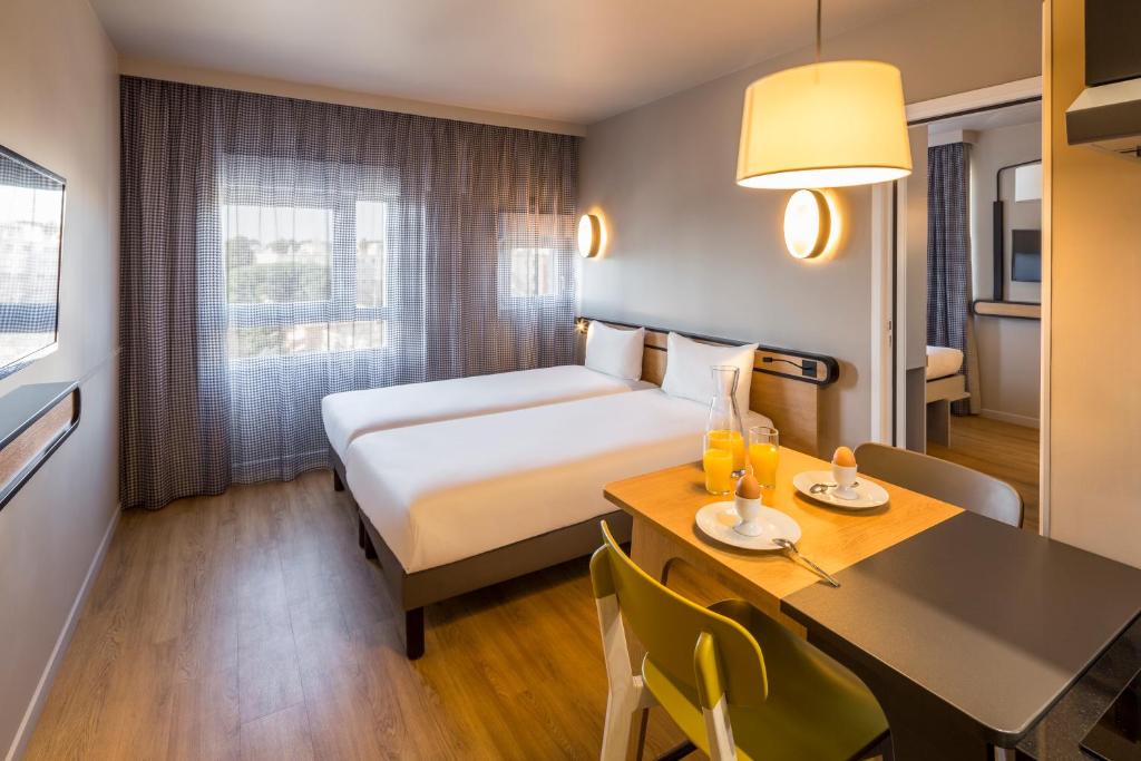 une chambre d'hôtel avec un lit et une table à manger dans l'établissement Aparthotel Adagio access Montpellier Centre, à Montpellier