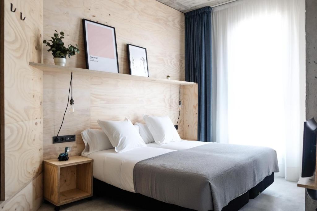 Un dormitorio con una gran cama blanca y una ventana en Talo Urban Rooms, en San Sebastián