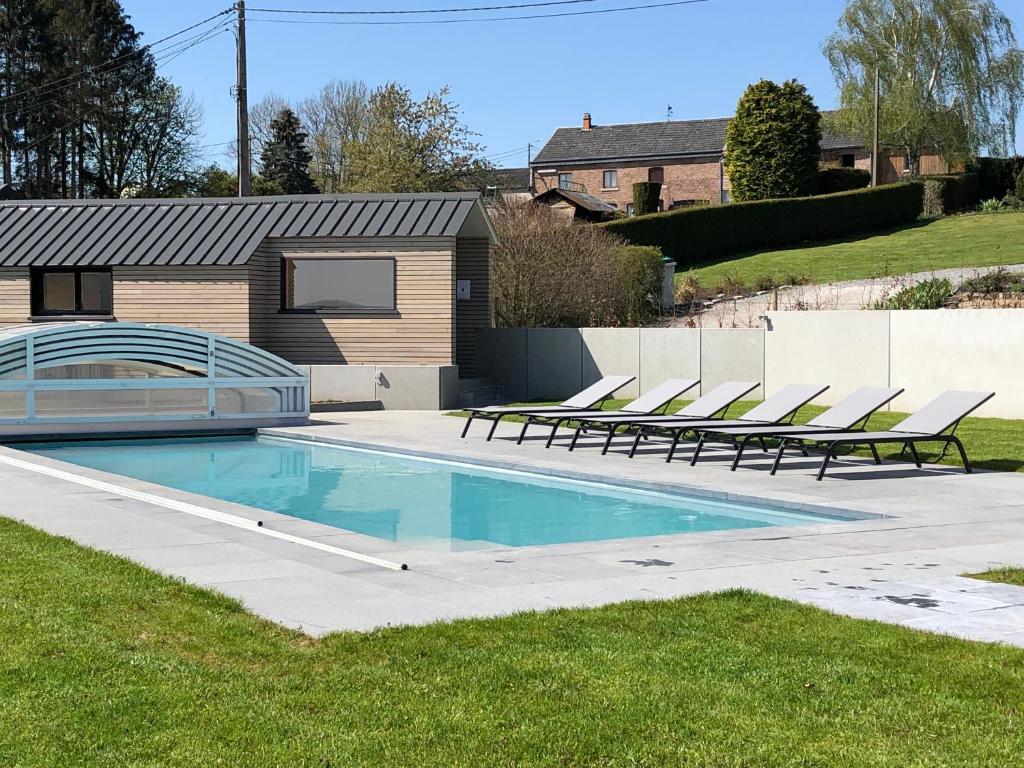 a swimming pool with lounge chairs in a yard at Vue d'en Haut in Durbuy