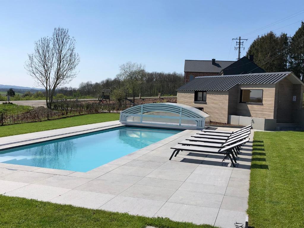 a swimming pool with two chairs and a bench at Vue d'en Haut in Durbuy